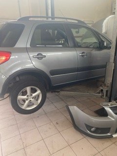 Samochód SUV na podnośniku ze zdjętym zderzakiem przednim podczas naprawy zawieszenia